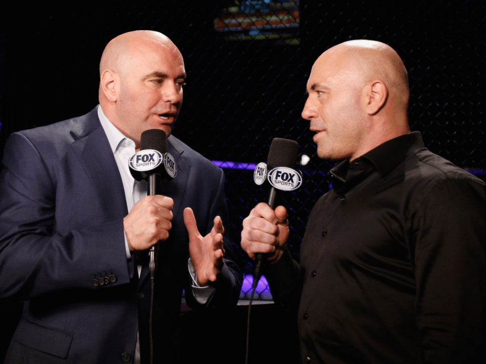 Two men in suits holding Fox Sports microphones are having a conversation.