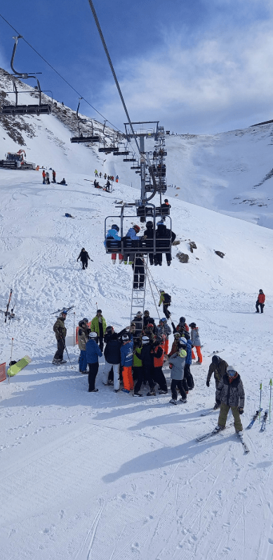 Skiers and snowboarders unloading from a chairlift on a snowy mountain.