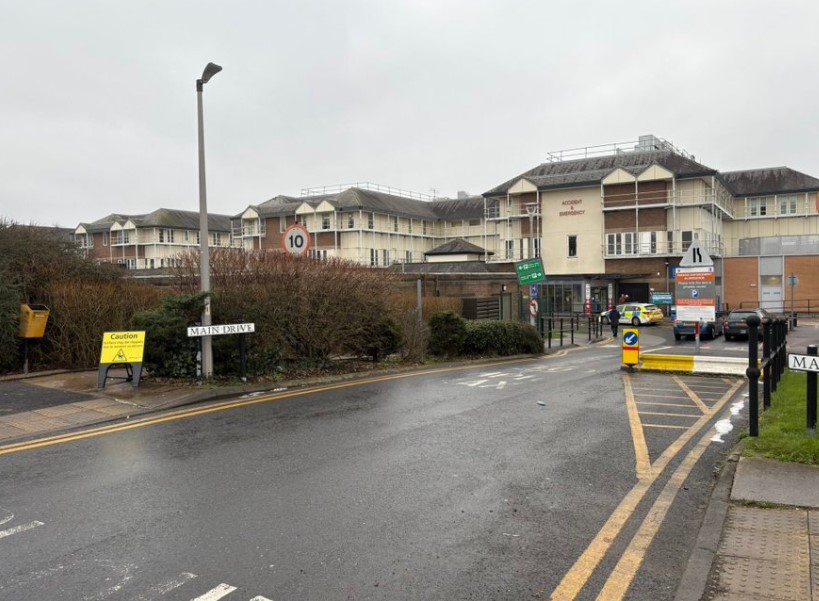 Hospital exterior with police car parked nearby.