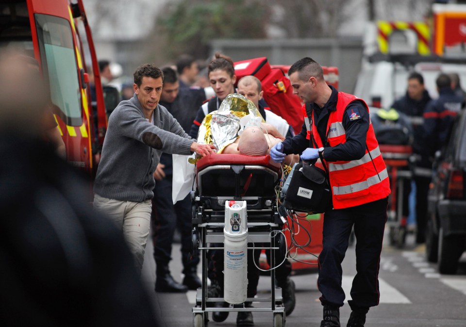 An injured person is transported to an ambulance after a shooting, at the French satirical newspaper Charlie Hebdo’s office, in Paris