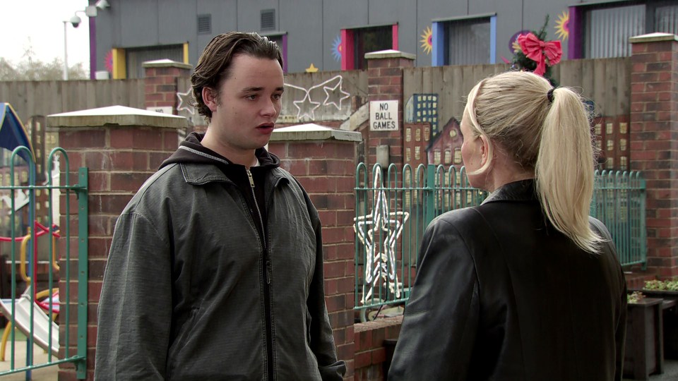 A man and woman talking outside near a playground.