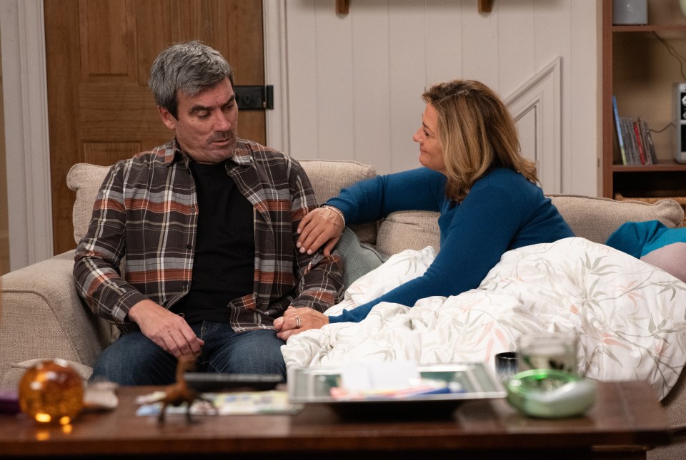 Moira Dingle and Cain Dingle on a couch; Moira is under a blanket.