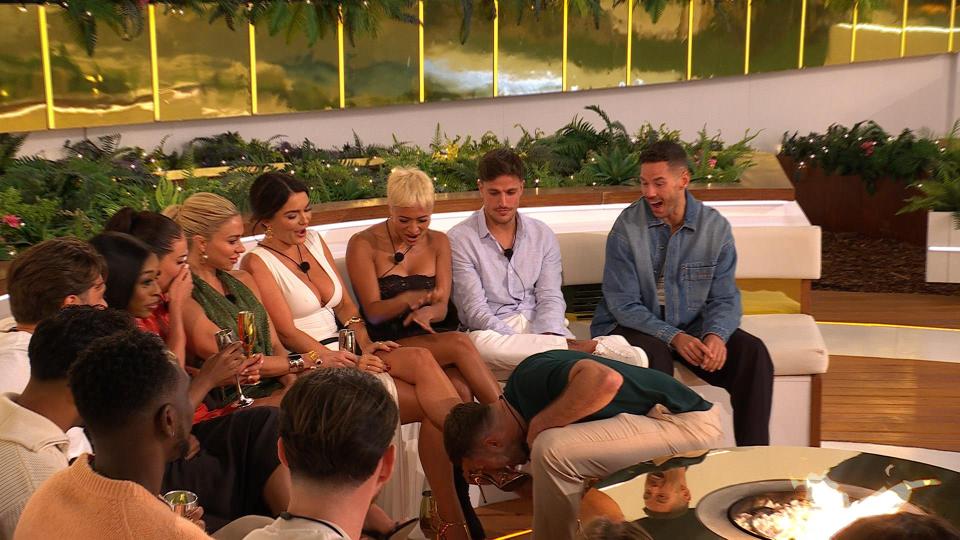 Love Island All Stars contestants reacting to a man kissing a woman's shoe.