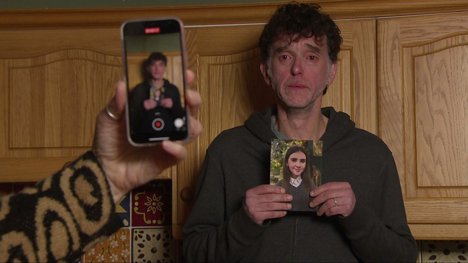 A man films an appeal video while holding a photograph of a young girl.