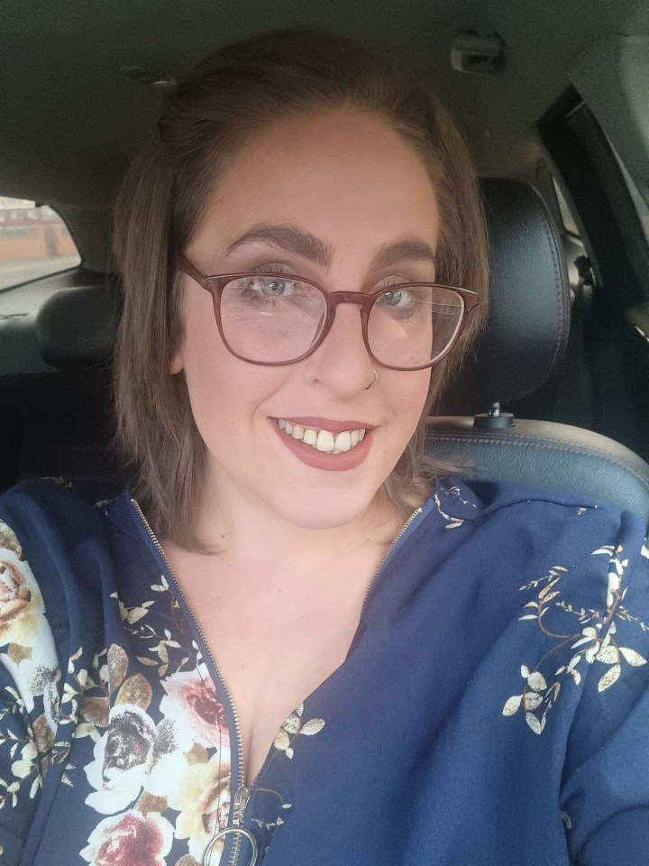 Woman in a floral shirt sitting in a car.