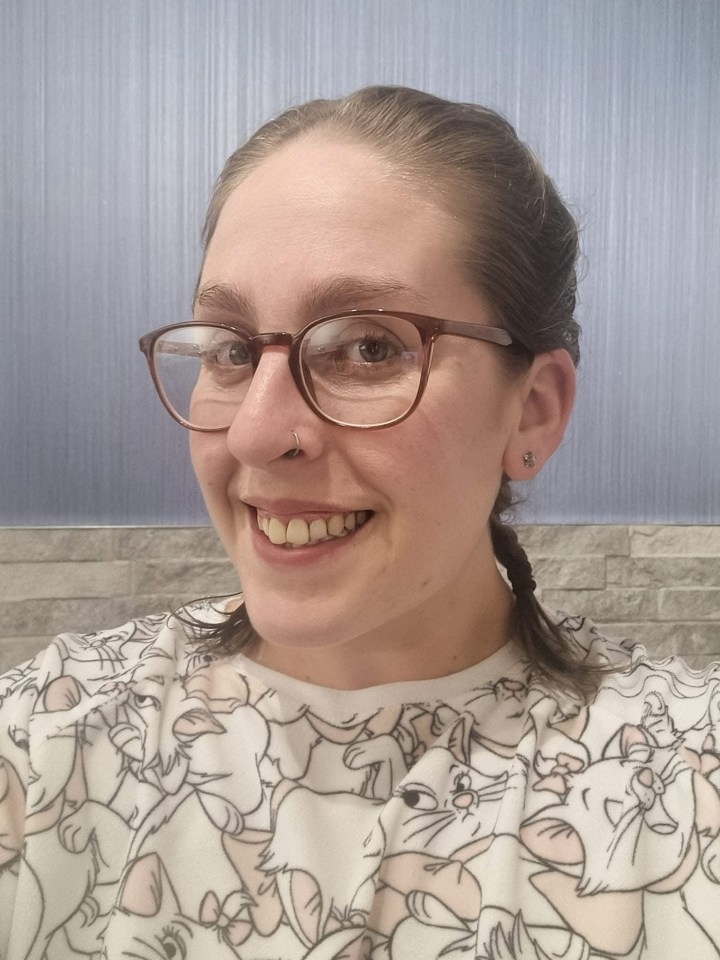 Woman wearing glasses and a cat-themed shirt.