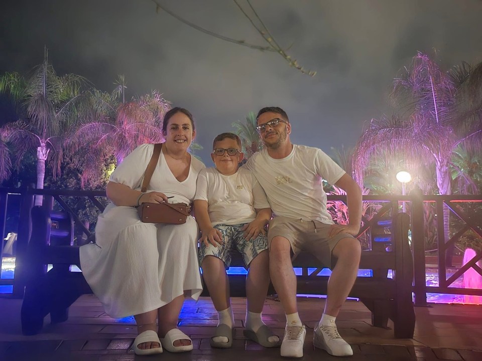 Family of three sitting on a bench at night.