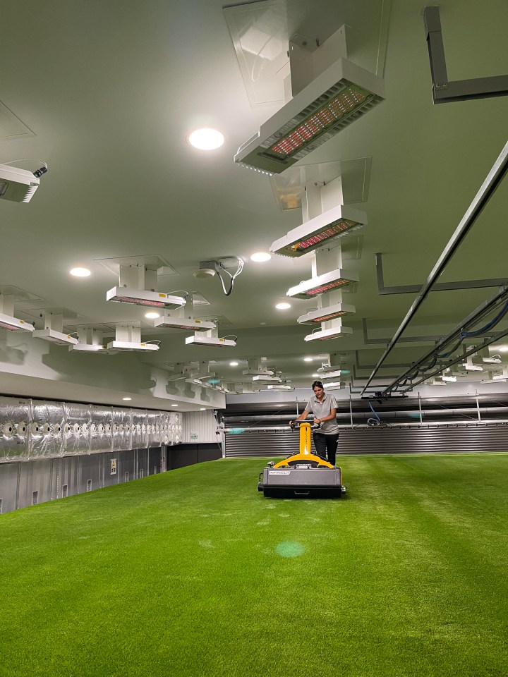 Technician operating machinery on a field of artificial turf in a climate-controlled laboratory.