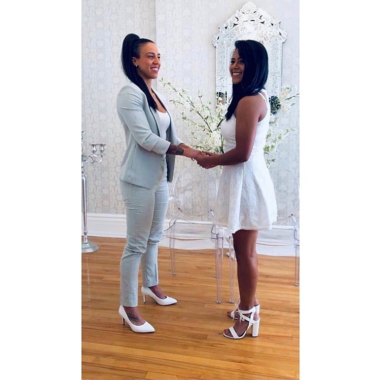 Two women holding hands at their wedding ceremony.