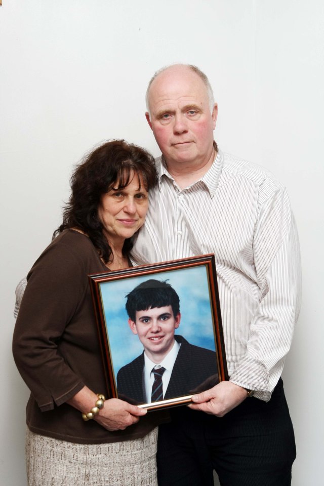 Parents holding a framed photo of their deceased son.