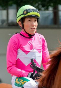 Jockey in pink silks atop a horse.