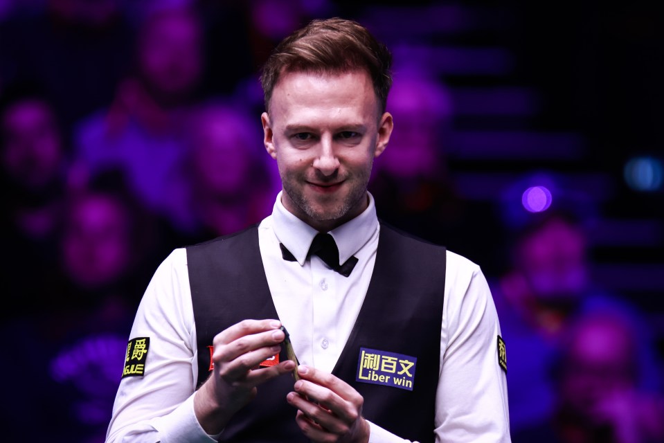 Judd Trump chalking his cue at a snooker match.