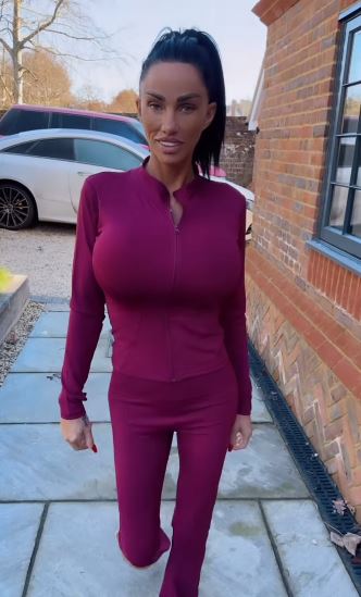 Katie Price walking down a driveway in a maroon zip-up jumpsuit.