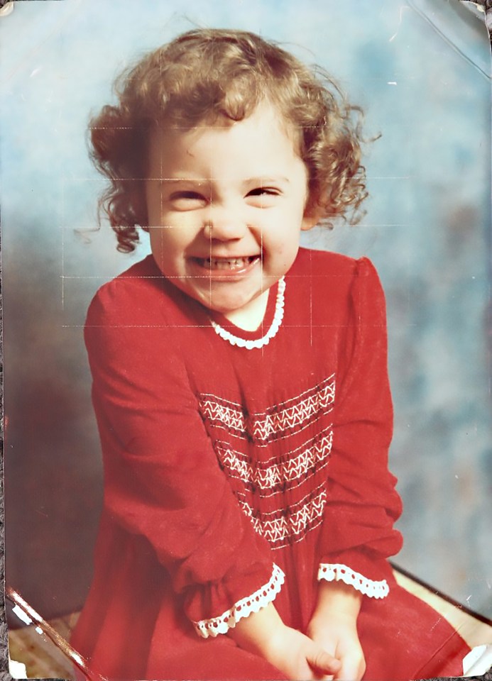 Photo of a toddler girl smiling in a red dress.