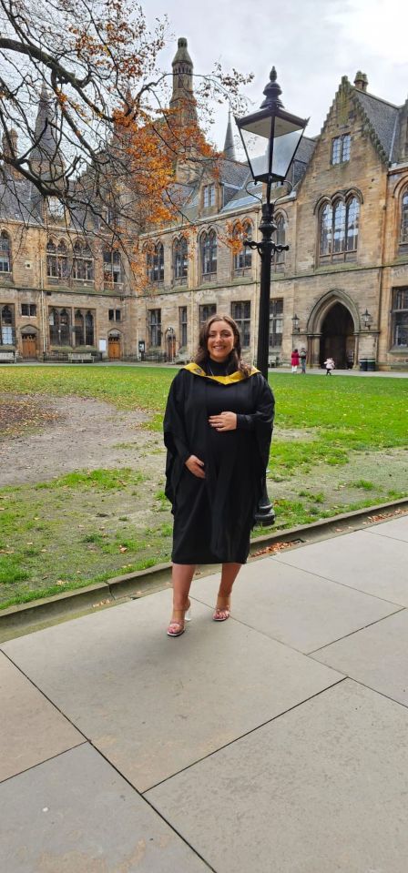 Pregnant woman in graduation gown in front of university building.