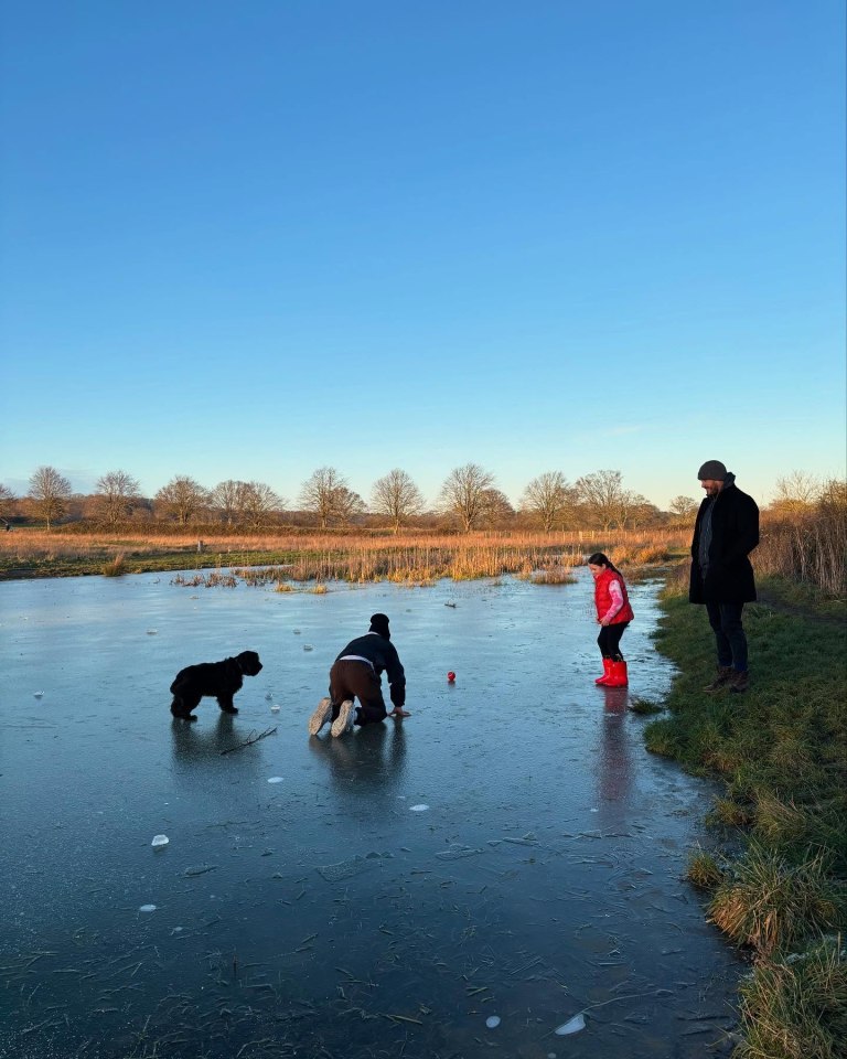 Family playing on a frozen lake with their dog.