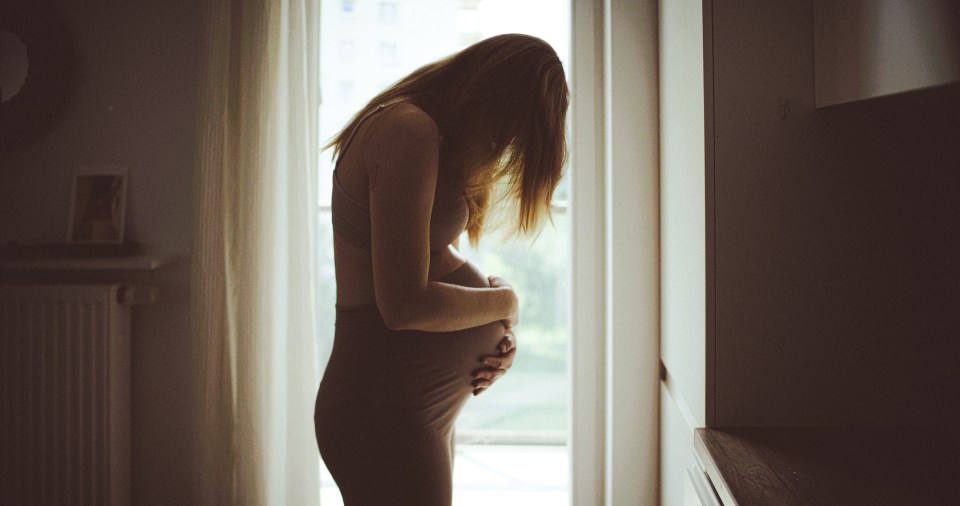 Pregnant woman holding her abdomen in pain.