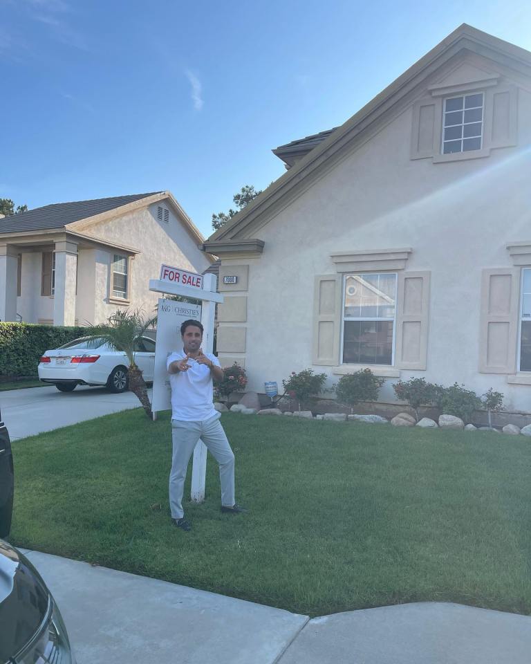 A realtor stands in front of a house for sale.