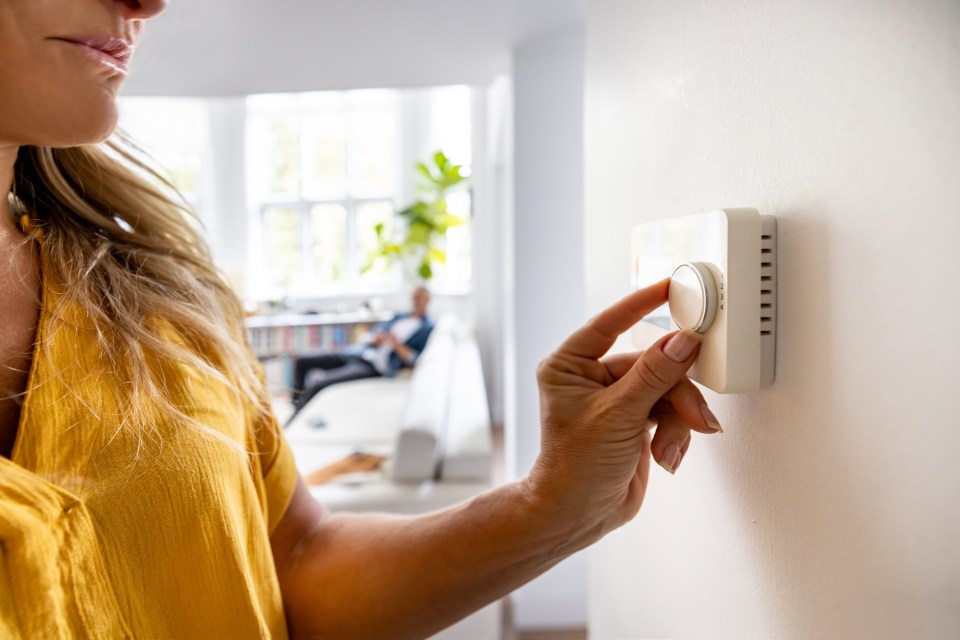 Woman adjusting thermostat.