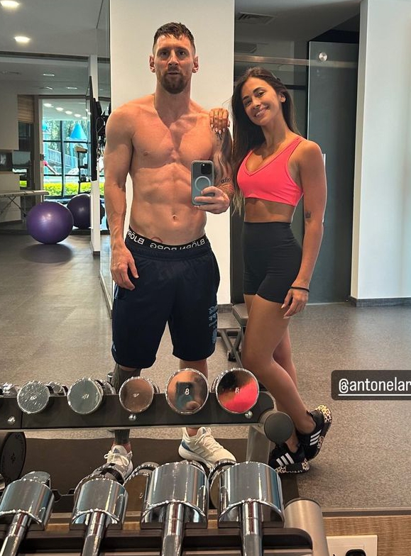 Lionel Messi and Antonela Roccuzzo in a gym, taking a selfie.