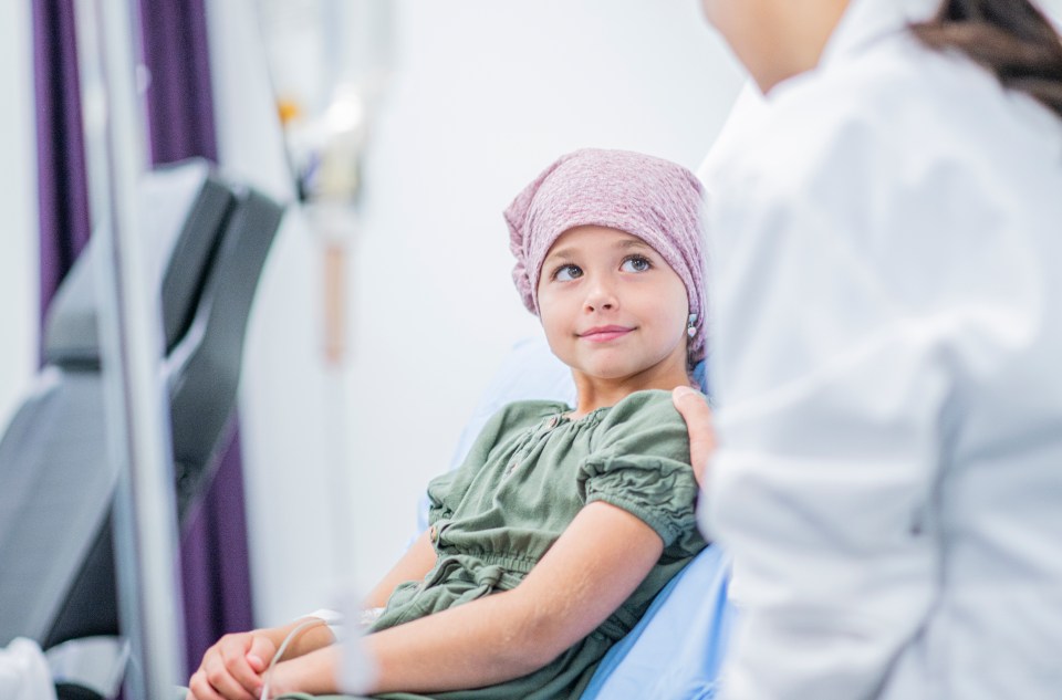 A young girl smiles at her doctor in a hospital room.