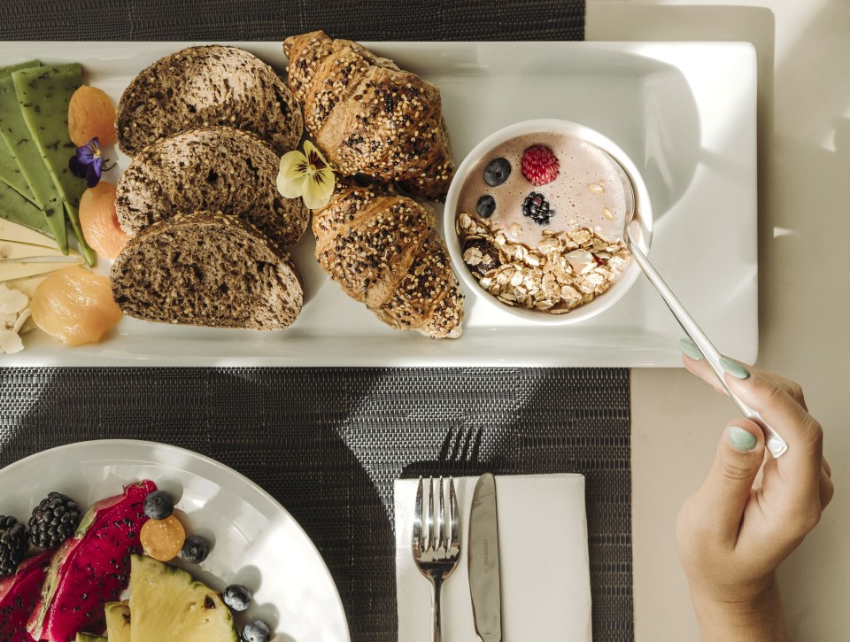 Breakfast platter with fruit, granola, yogurt, croissants, and bread.