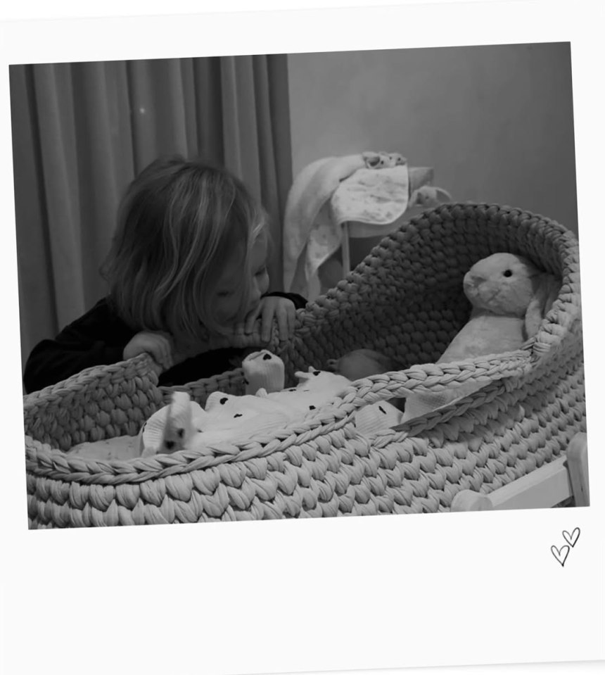 A toddler looking into a crocheted baby bassinet.