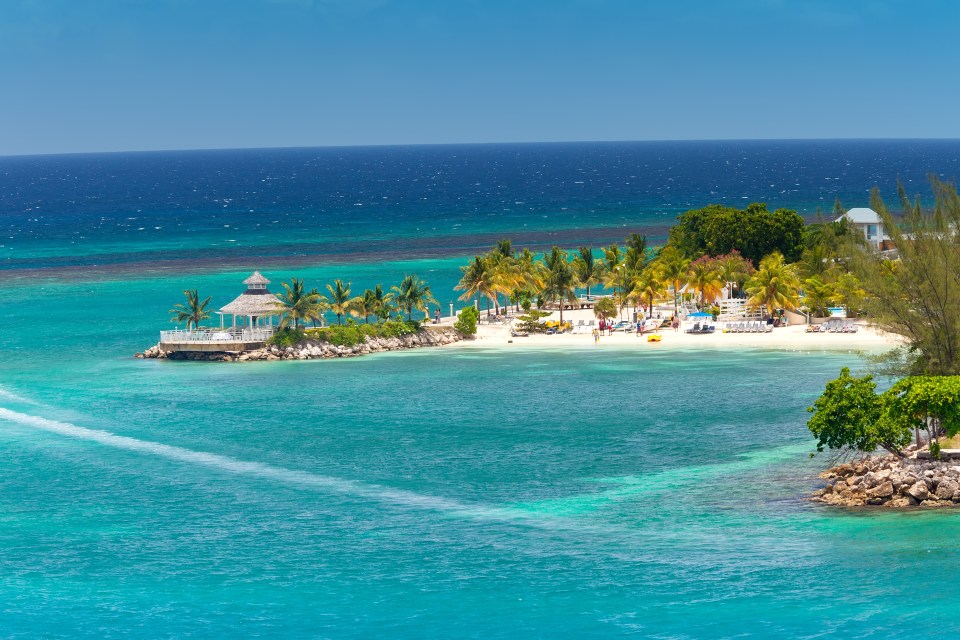 Tropical island beach scene with gazebo and palm trees.