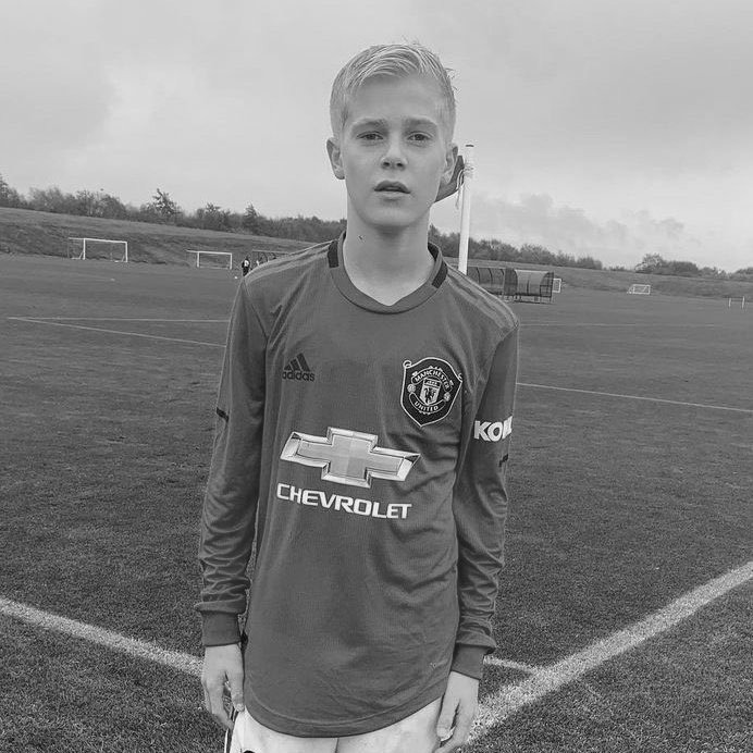 Boy in Manchester United jersey on soccer field.