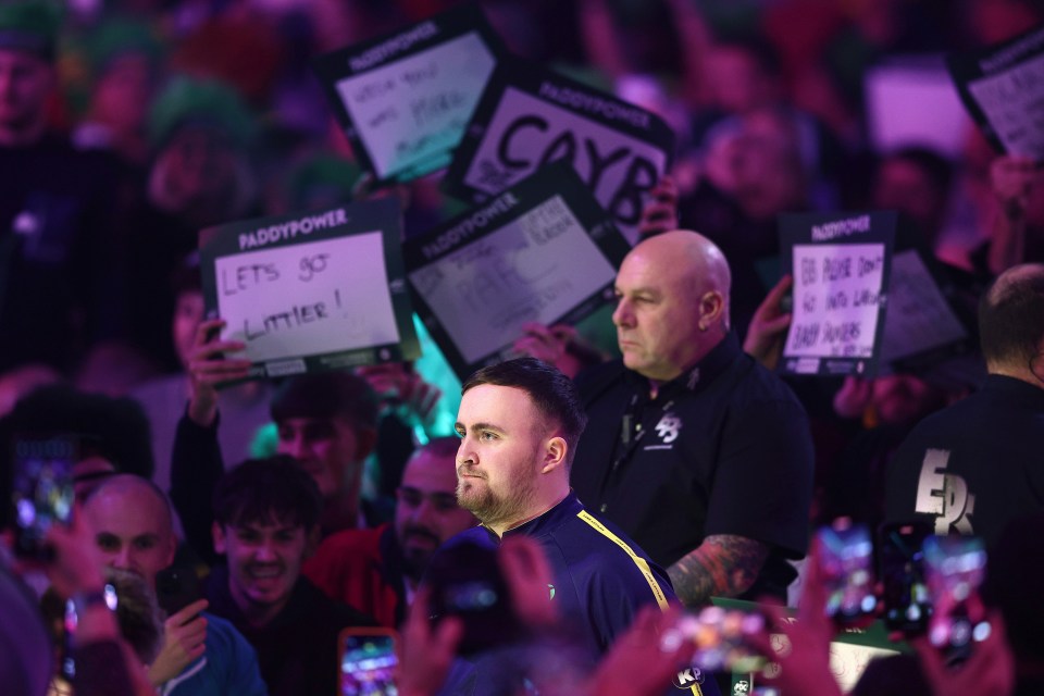 Luke Littler entering a darts arena.