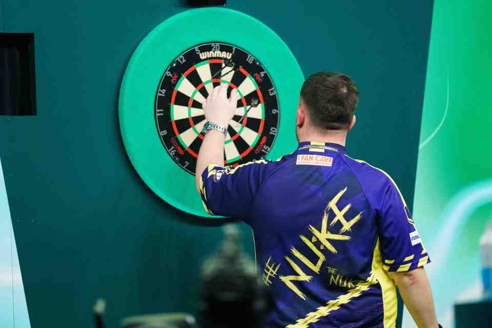 Luke Littler throwing darts at a dartboard.