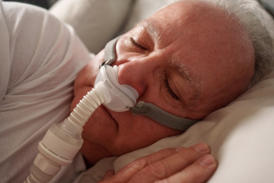 Senior man sleeping with CPAP machine.