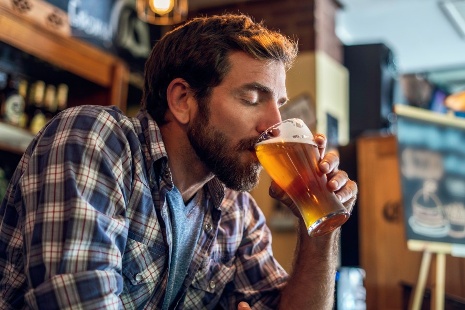 Man with eyes closed enjoying a beer at a bar.