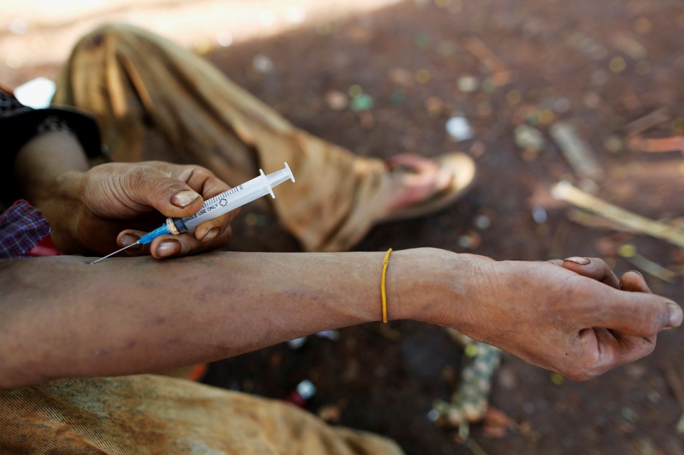 A person injecting heroin into their arm.