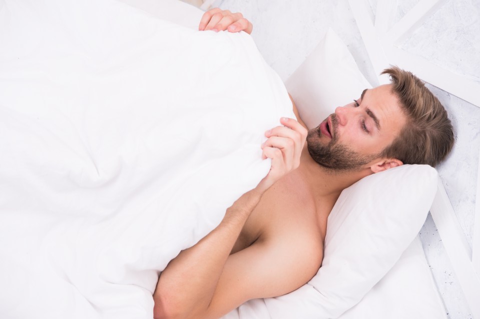 Man waking up in bed, looking surprised.