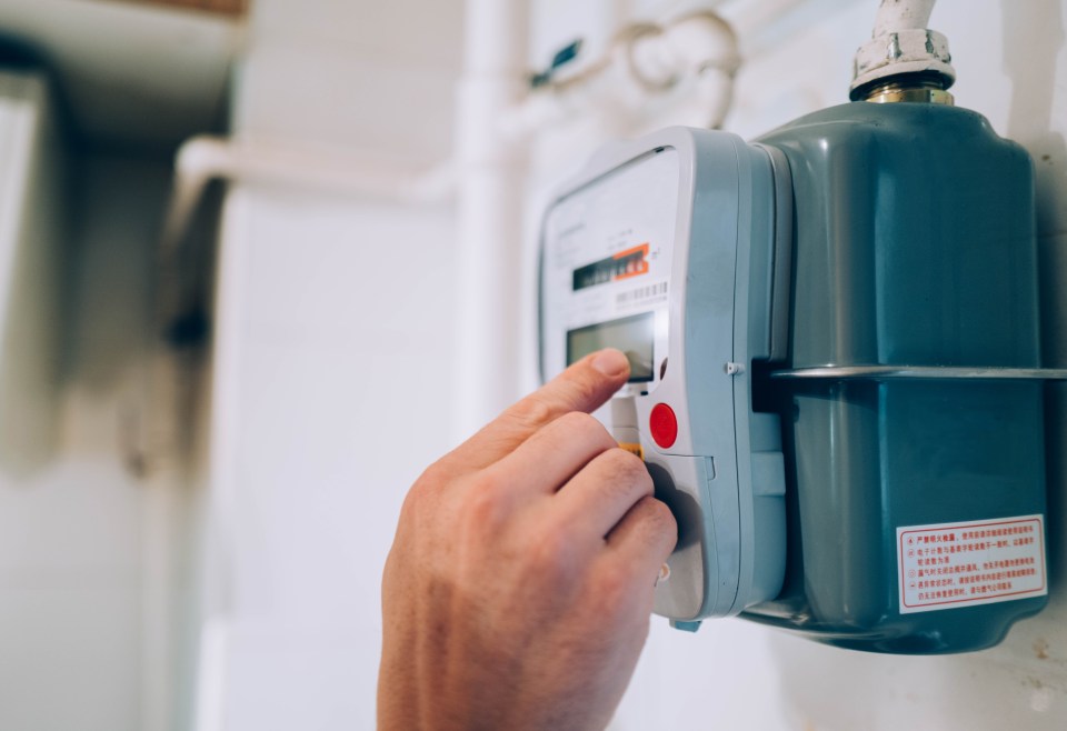 A person's hand checking a gas meter during an energy crisis.