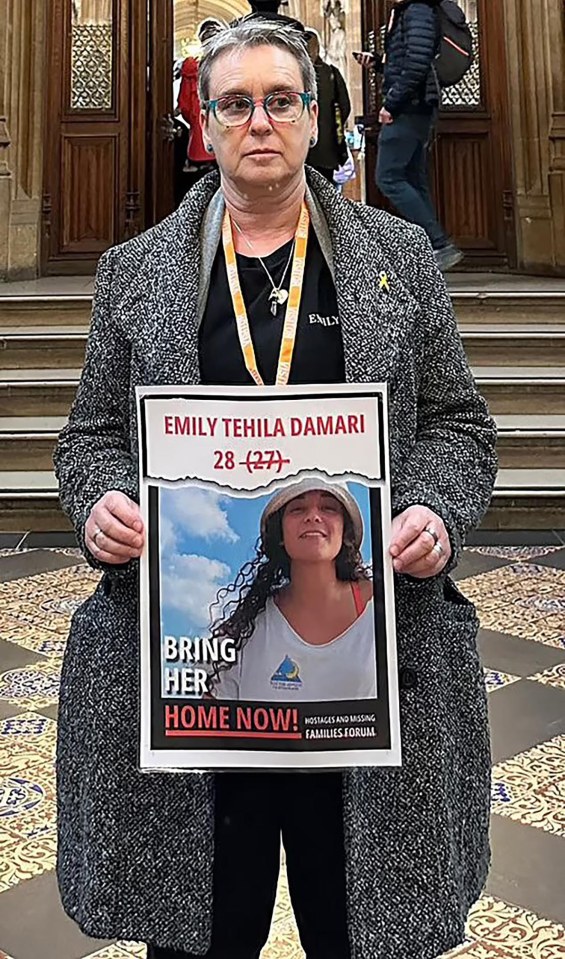 Woman holding poster seeking return of missing daughter, Emily Tehila Damari.