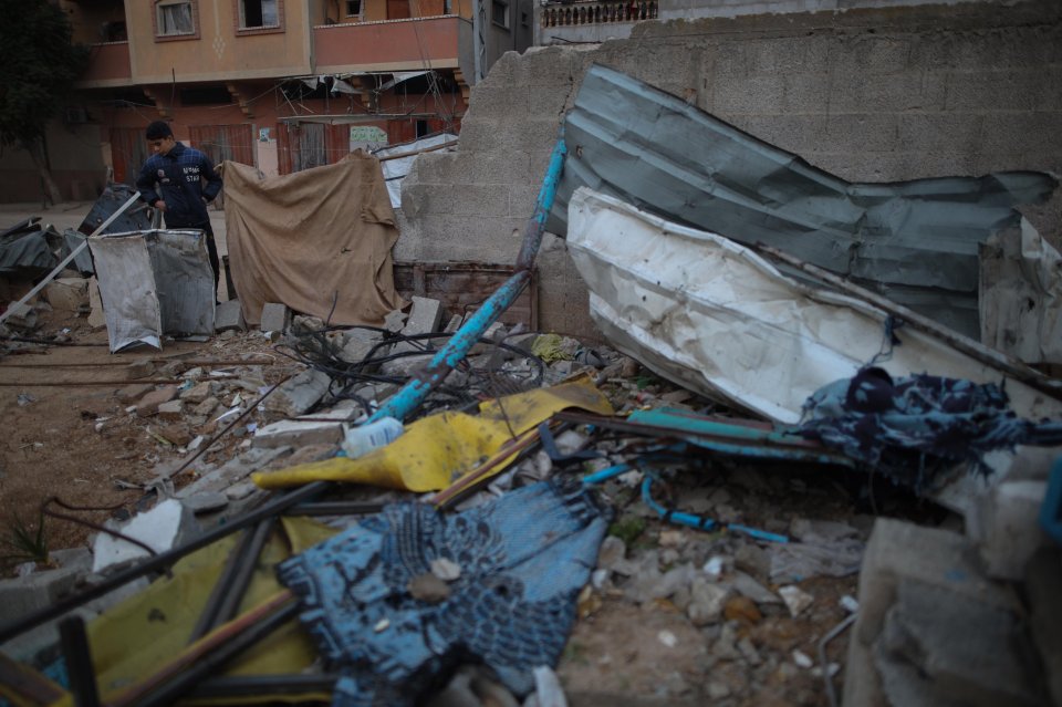 A Palestinian man amidst the rubble of a destroyed tent in a refugee camp.