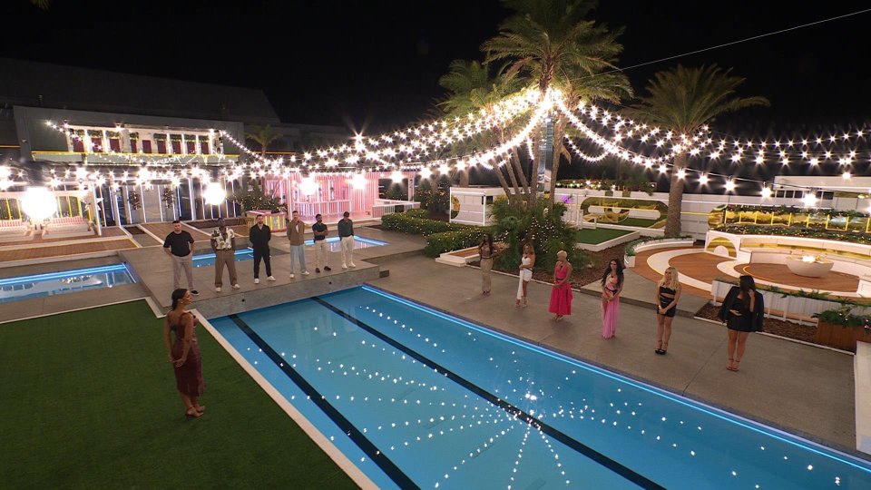 "Love Island: All Stars" contestants gathered by the pool at night.