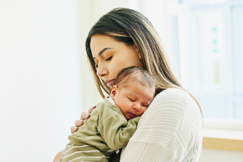 Mother holding a sleeping newborn baby.