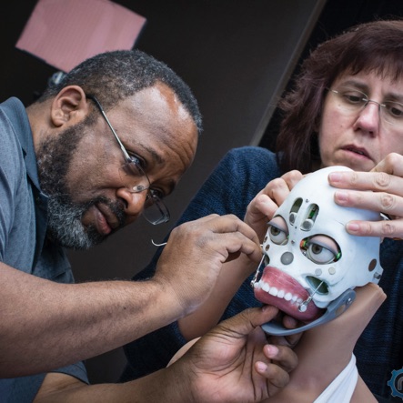 Two engineers working on a robot head prototype.