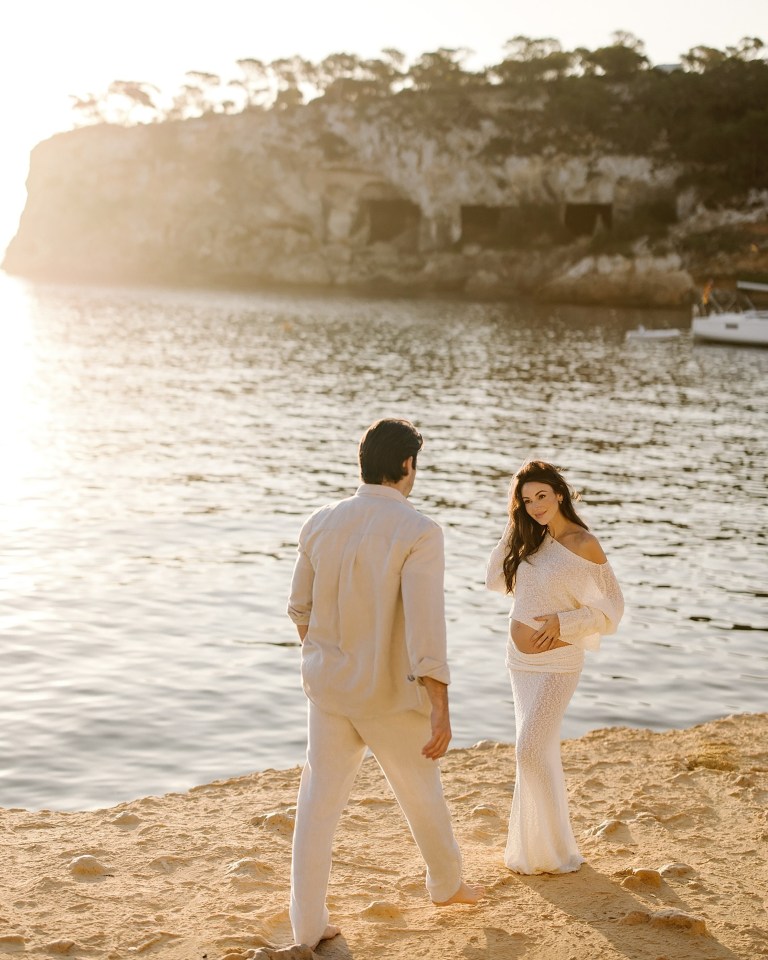 Pregnant woman and man on a beach.