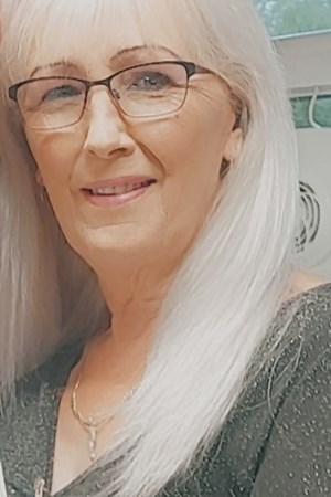 Portrait of a woman with long white hair and glasses.