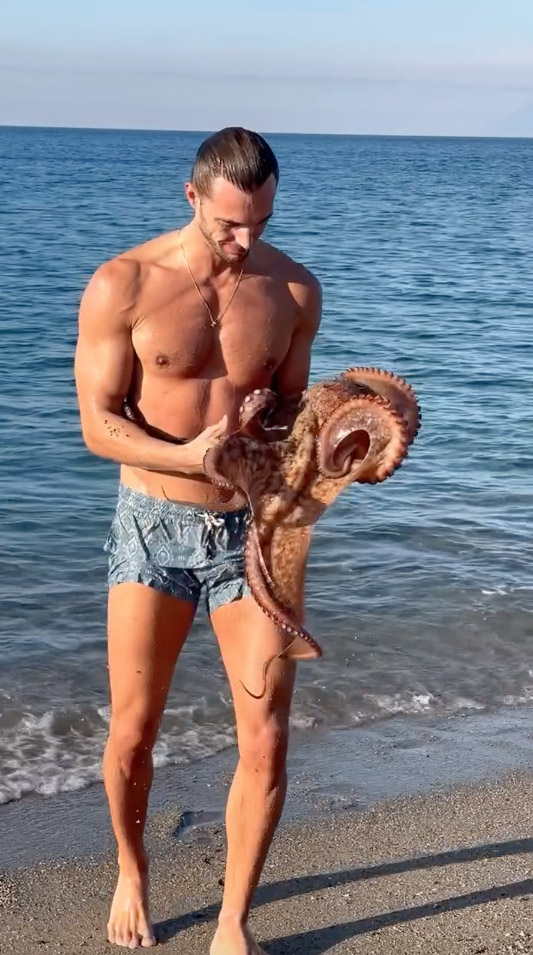 Man holding an octopus on a beach.