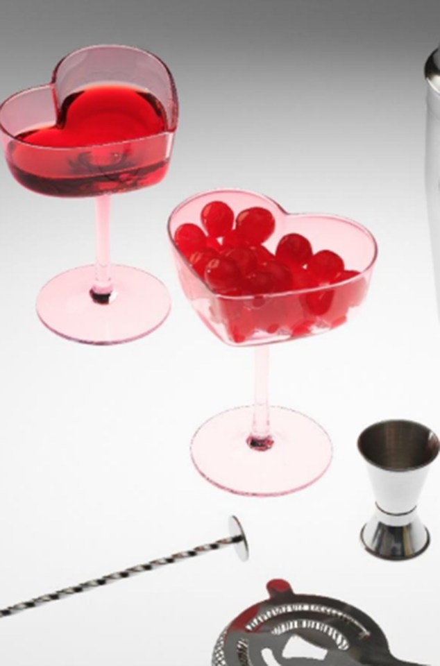 Heart-shaped glasses with red liquid and cherries.