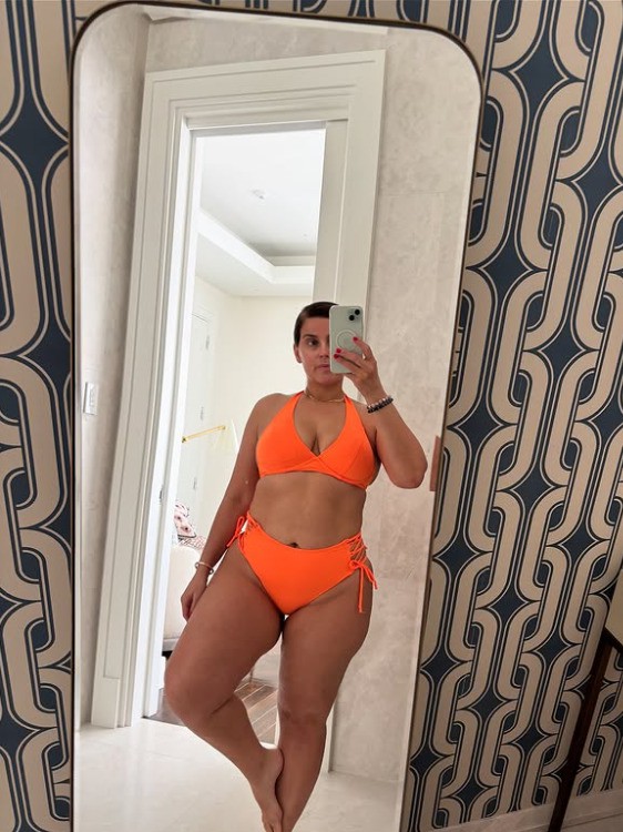 Woman in orange bikini taking a selfie in a mirror.