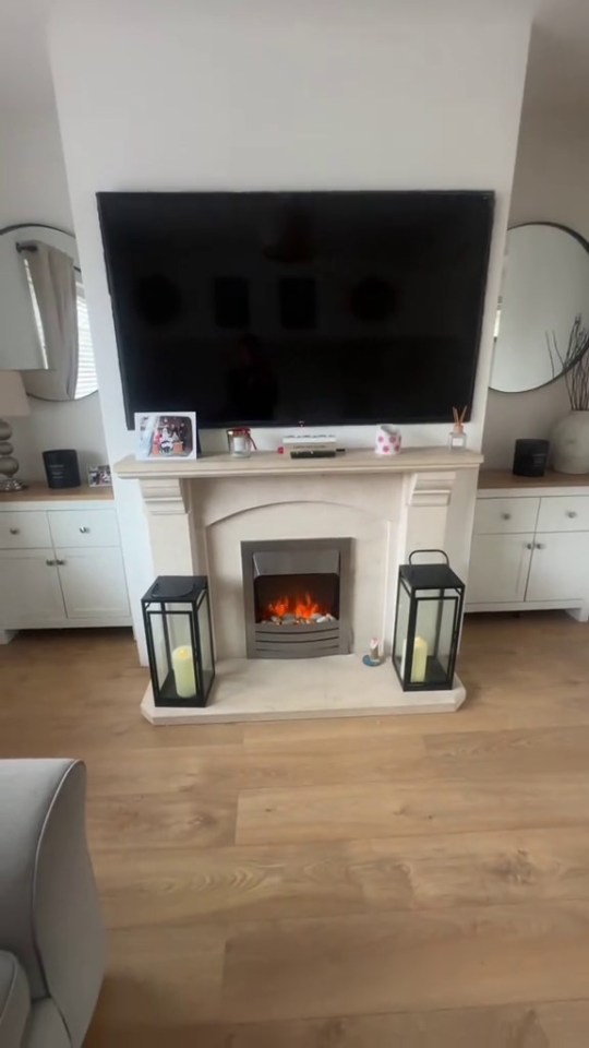 Living room with fireplace, TV, and light wood floors.