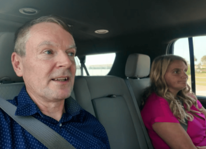 A man and woman sitting in the backseat of a car.