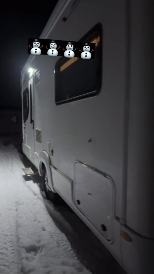 Motorhome parked in the snow with four snowmen displayed on the side.