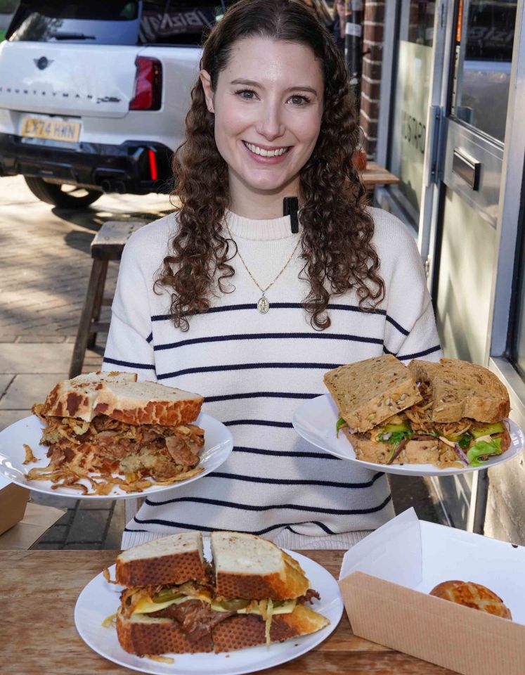 Woman holding three large sandwiches from a sandwich shop.